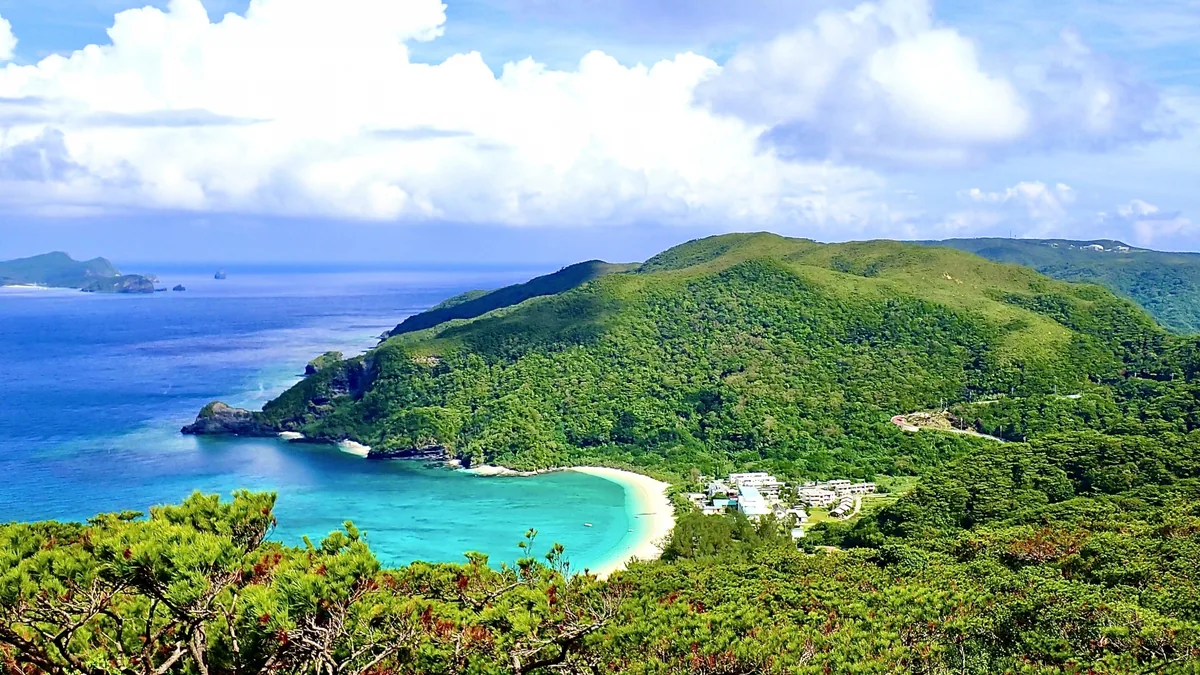 A turquoise bay and sandy beach surrounded by green hills on Tokashiki Island
