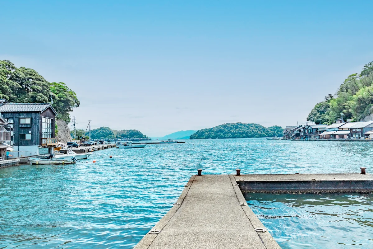A short concrete pier extending into the blue-green water of Ine Bay