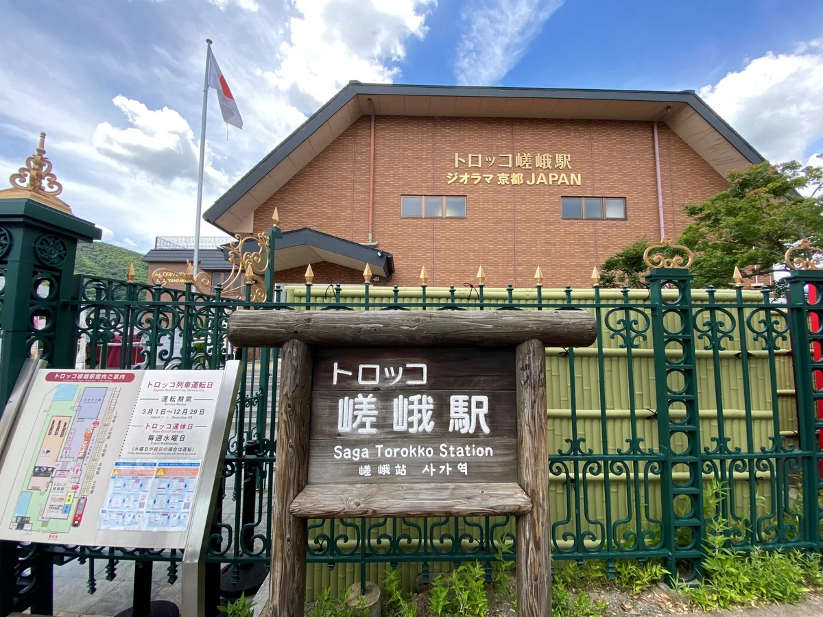 The brick Torokko Saga Station building behind a wooden sign reading Saga Torokko Station