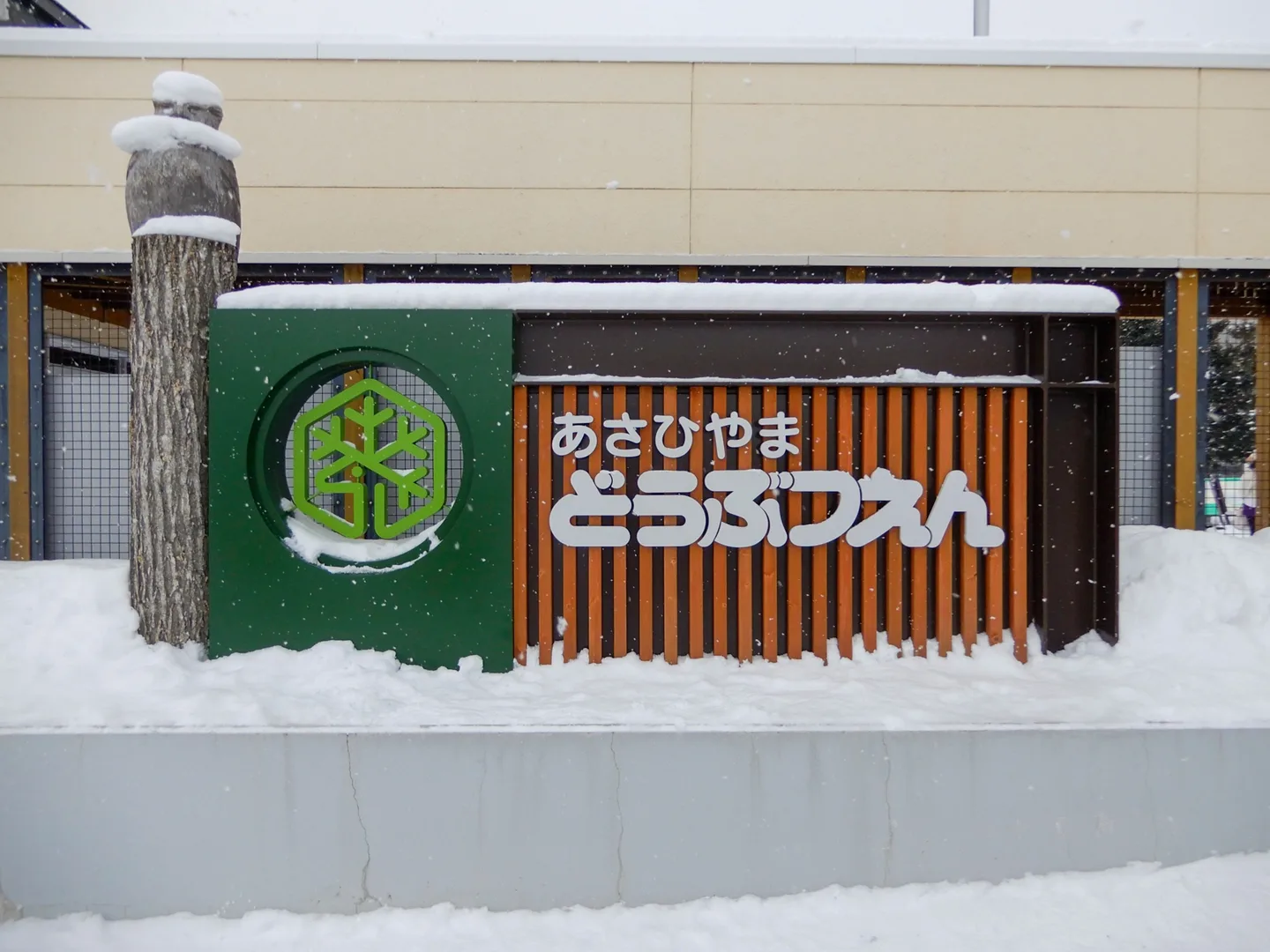 Snow around a wooden Asahiyama Zoo entrance sign