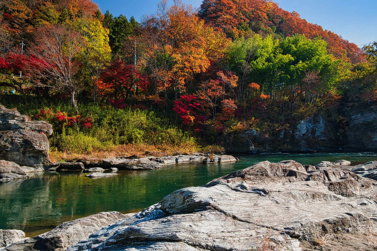 Autumn forest reflected beside the rocky Arakawa River in Nagatoro