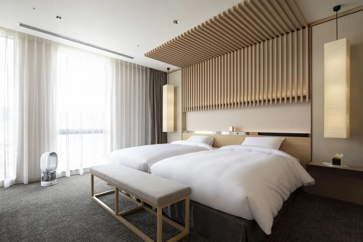 Two beds and large windows in a guest room at Cross Hotel Kyoto