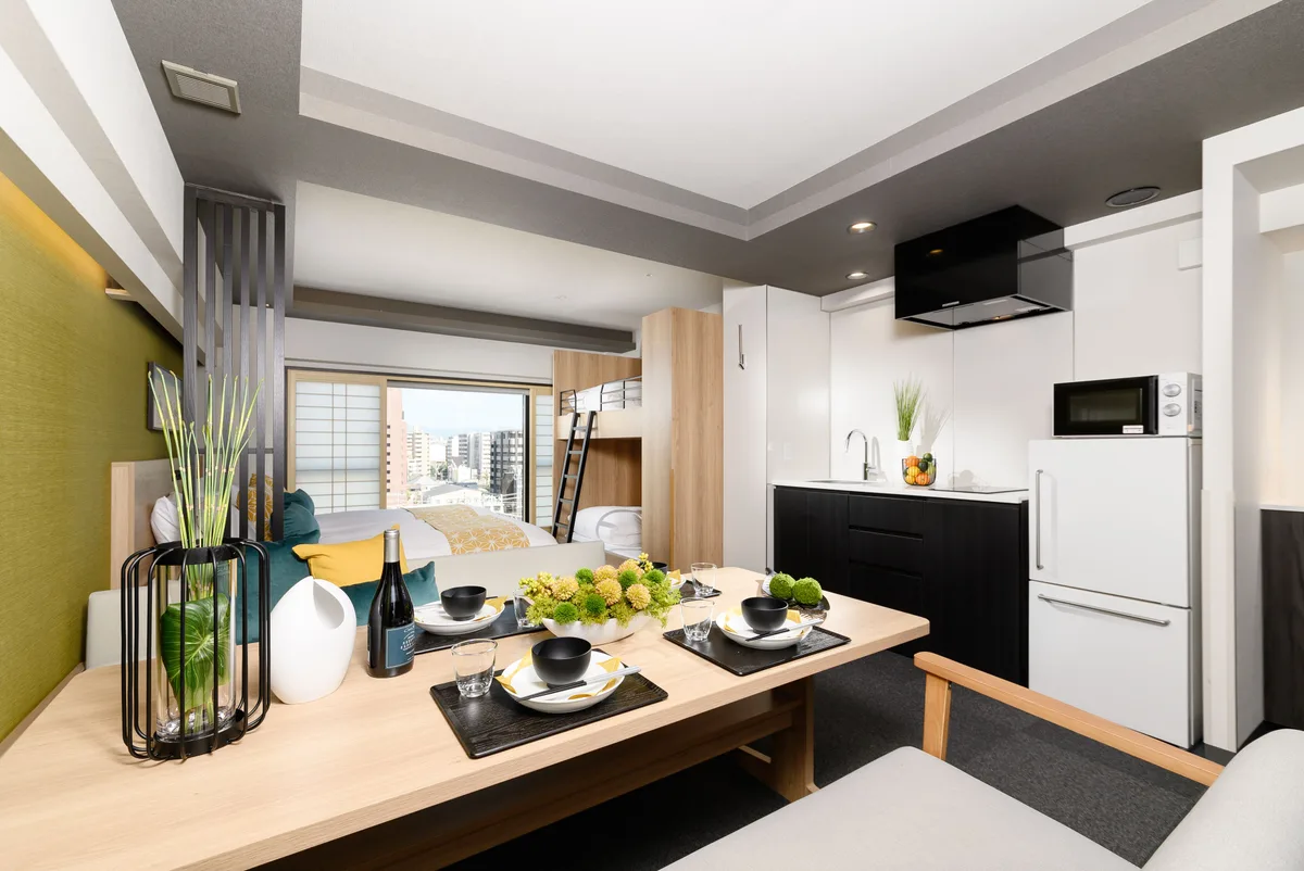 A dining table, kitchenette and beds in an apartment at MIMARU Kyoto Station