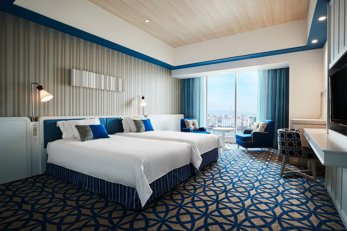 A blue-and-white guest room with two visible beds at Hotel Universal Port