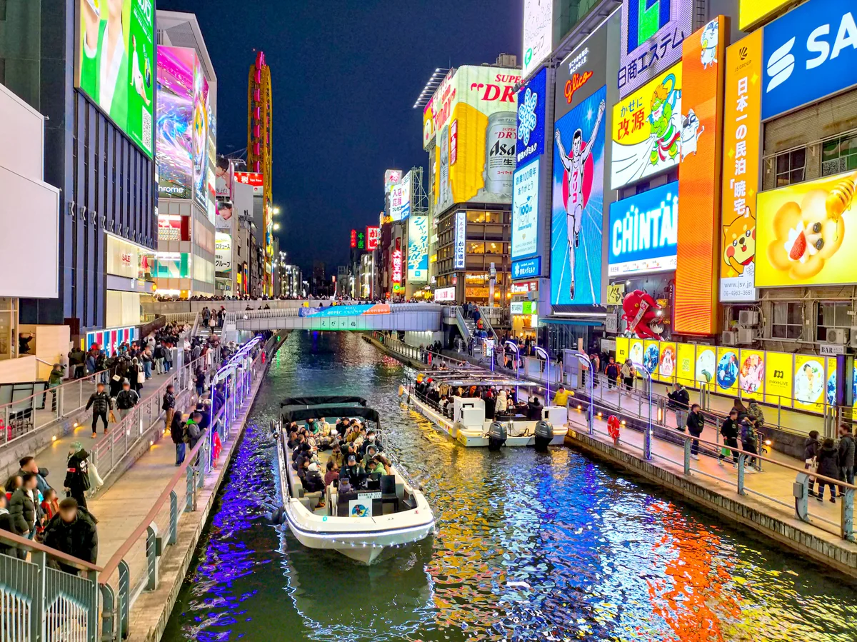 Illuminated billboards and sightseeing boats on the Dotonbori canal at night