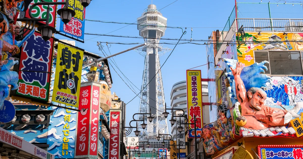 Tsutenkaku tower framed by colorful restaurant signs in Shinsekai