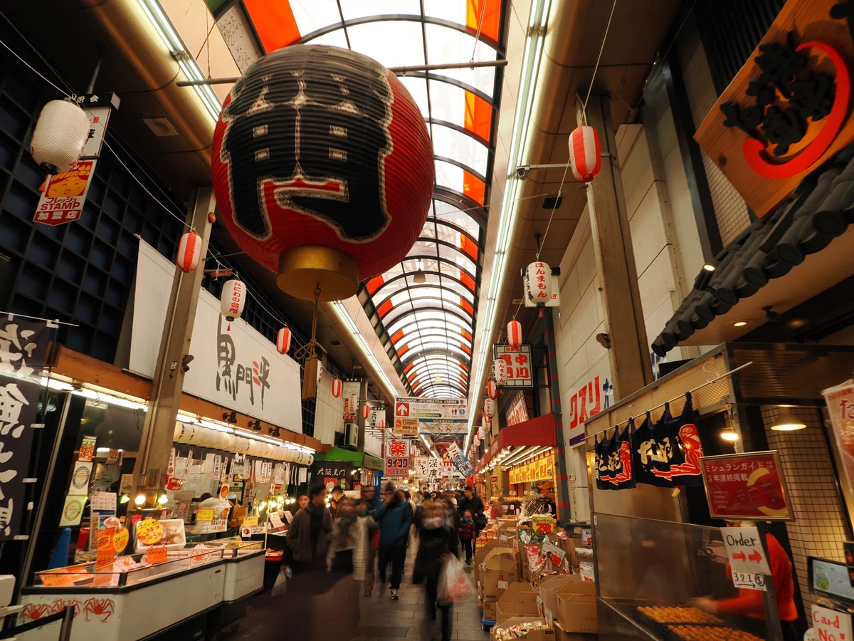 Shoppers and storefronts along Kuromon Market's covered arcade