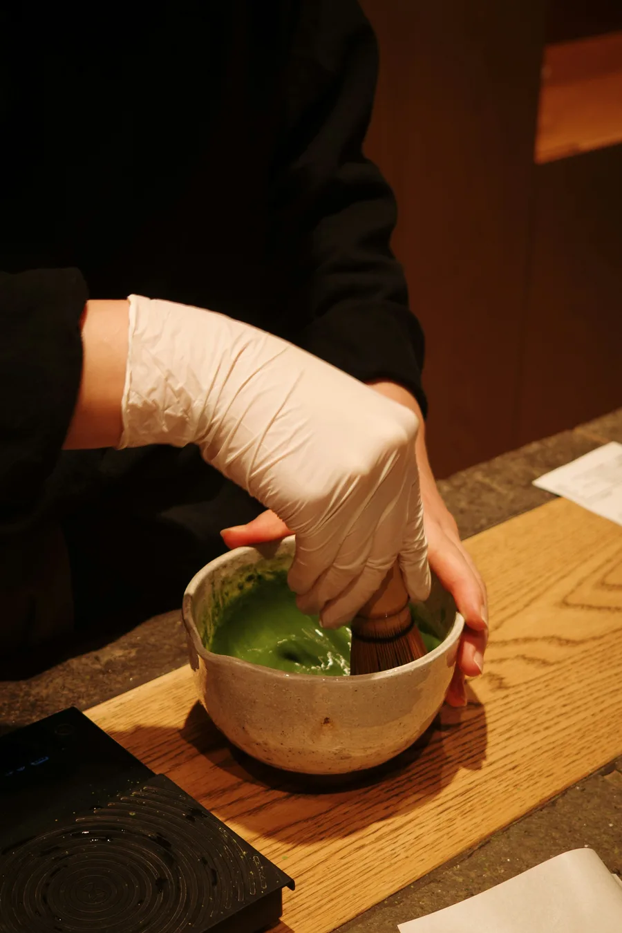 A gloved hand whisking matcha in Kiyomizu, Kyoto