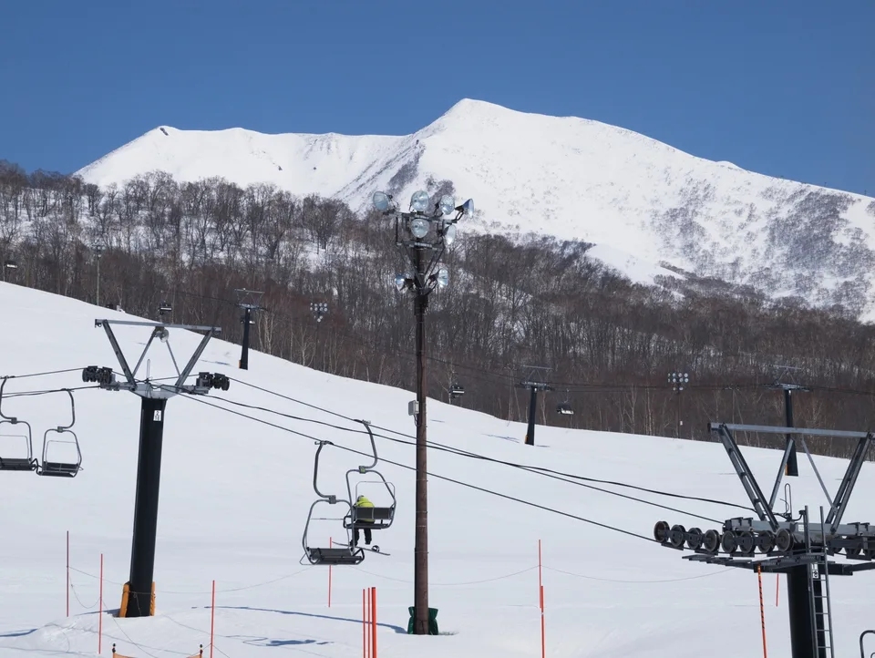 Chairlifts below a snow-covered mountain in Niseko
