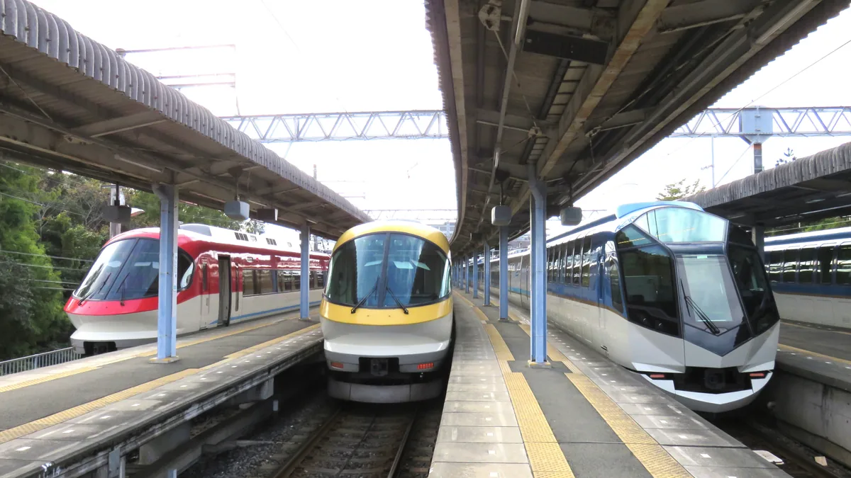 Three Kintetsu limited express trains standing side by side at station platforms