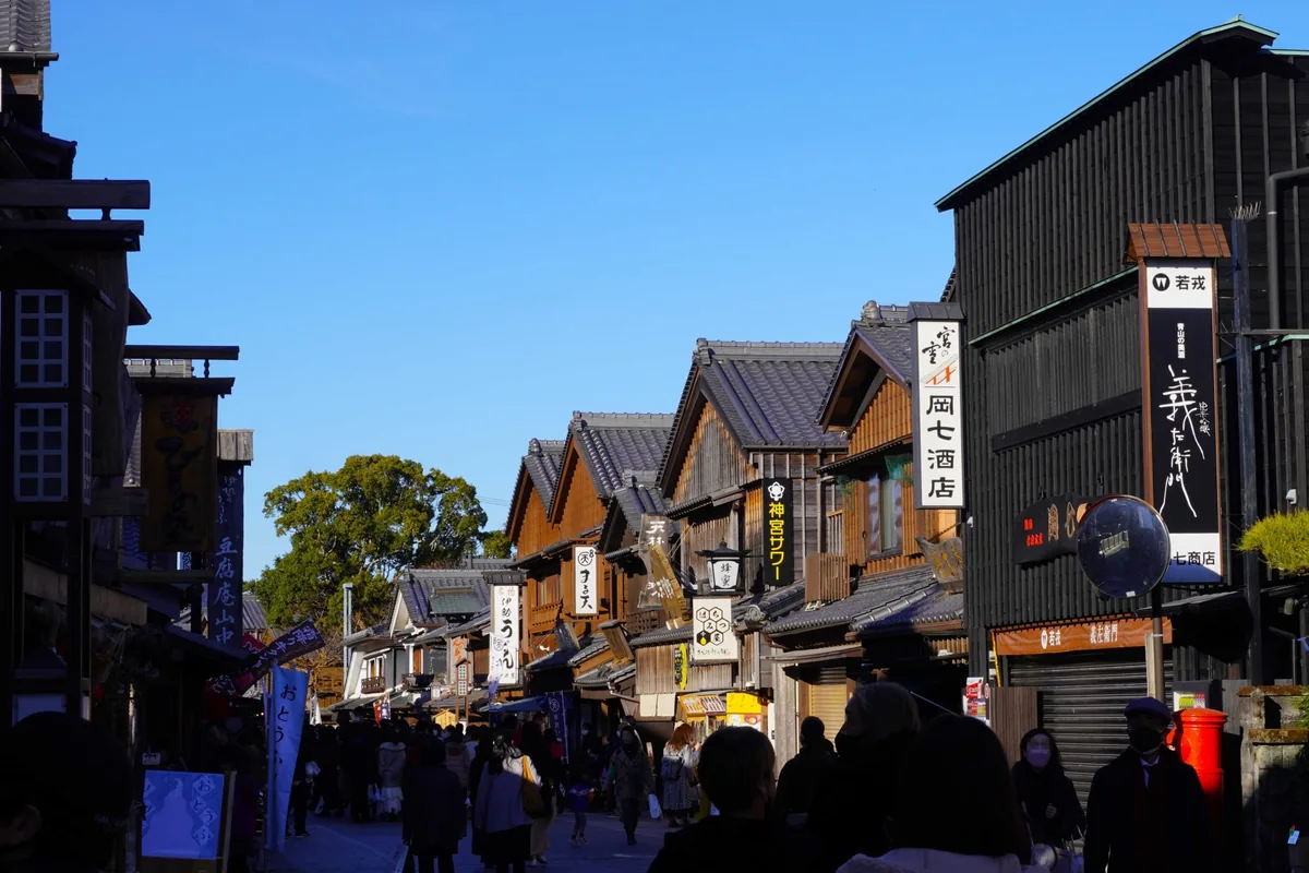 Visitors walking past shops with tiled roofs and hanging signs in Oharaimachi