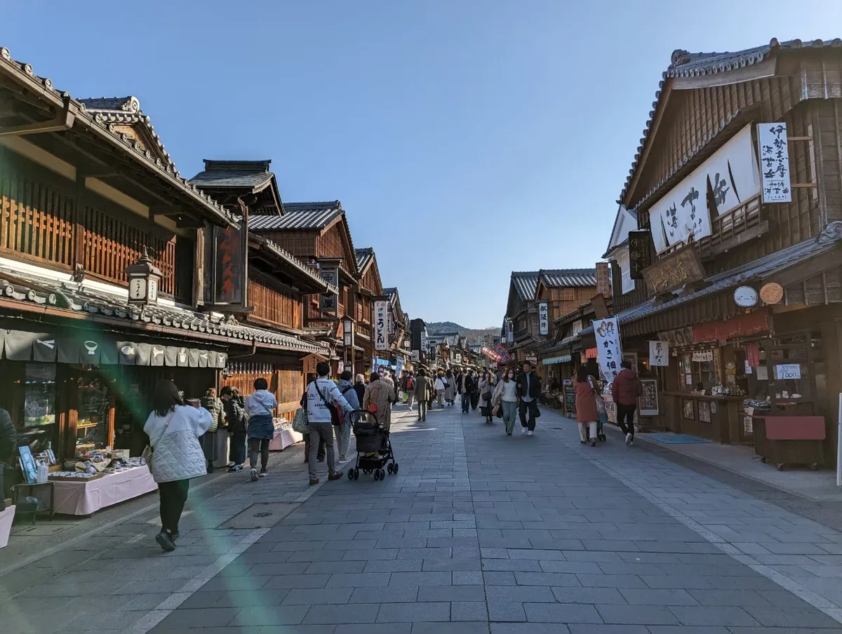 Visitors strolling along Oharaimachi between traditional wooden shops under a blue sky