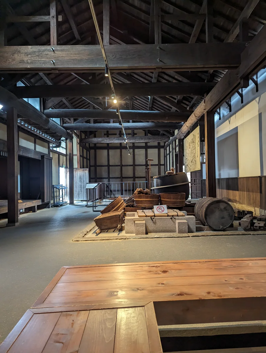 Exposed wooden roof beams and historic brewing equipment inside the former Okada residence in Itami