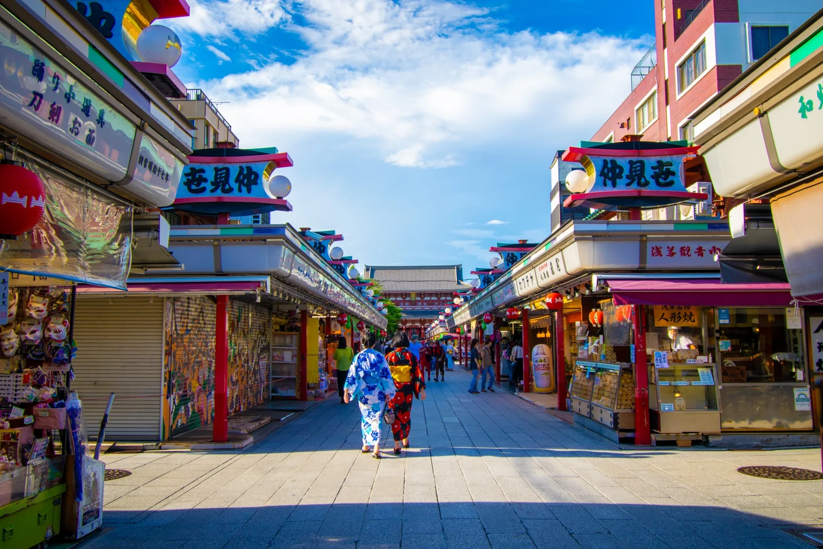 Two visitors in yukata walking along Nakamise toward Sensoji