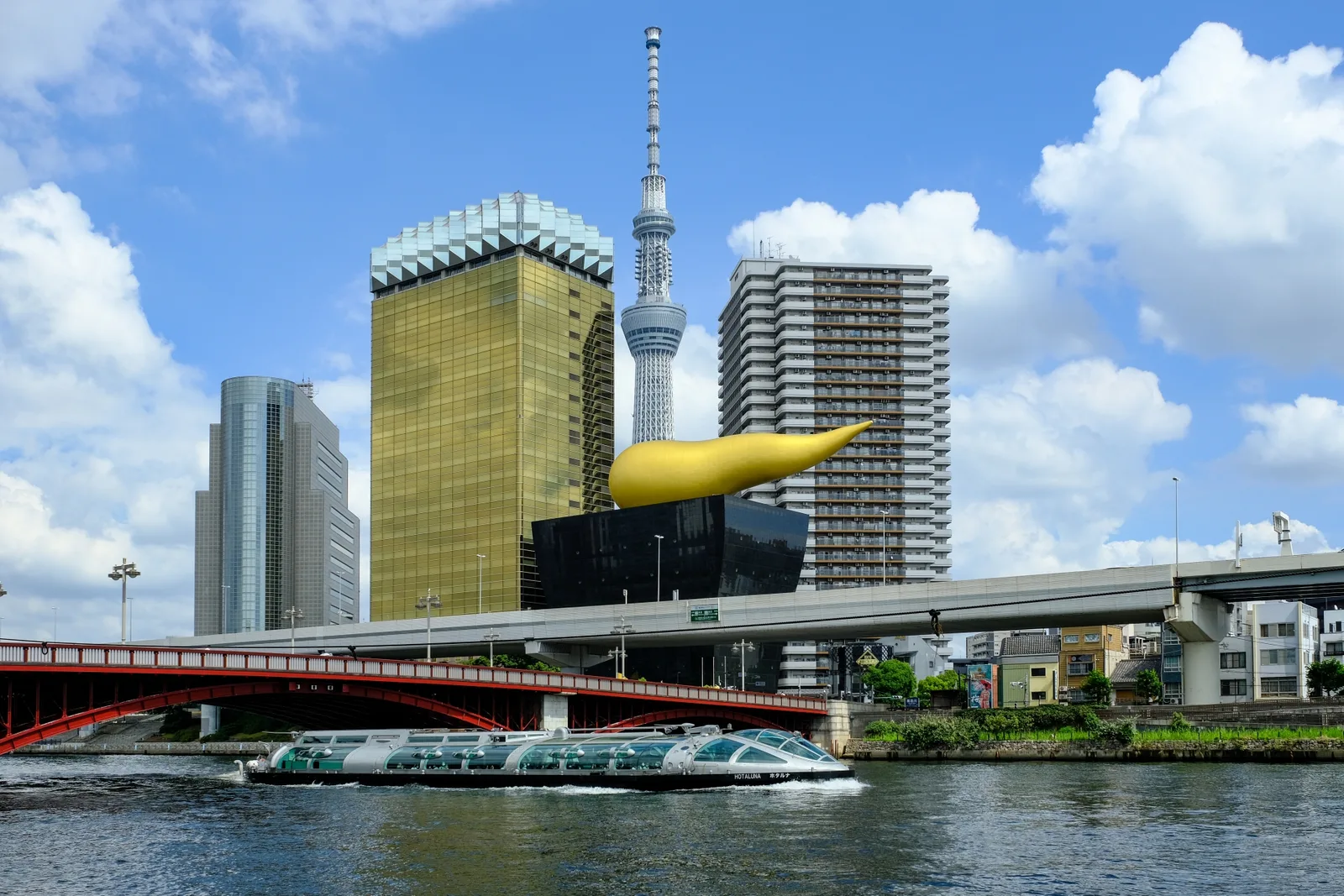 A water bus passing Azumabashi with Tokyo Skytree and the Asahi buildings beyond