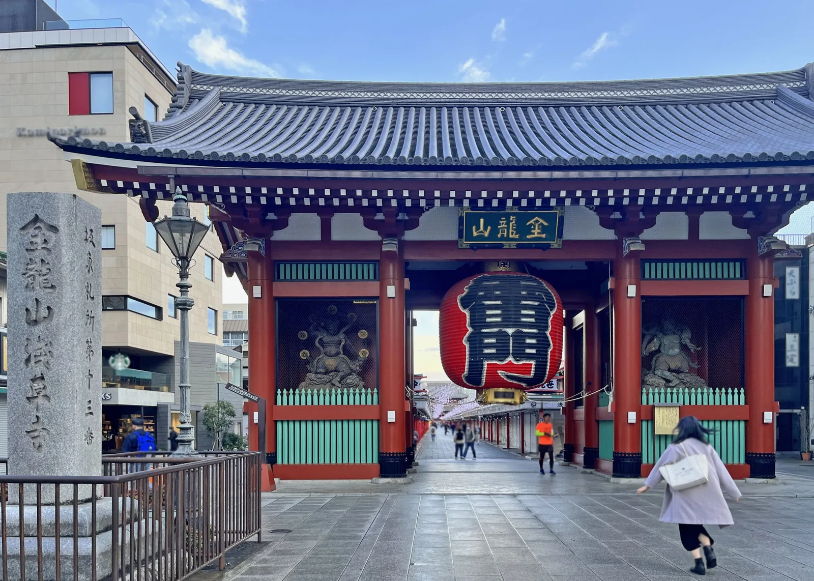 A traveler approaching the red Kaminarimon gate on a quiet morning in Asakusa