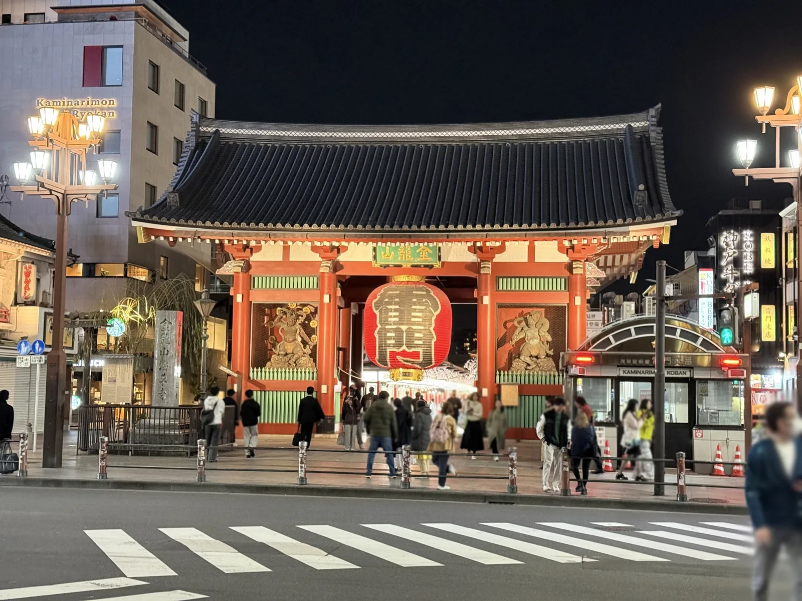 Kaminarimon illuminated at night as visitors cross the street