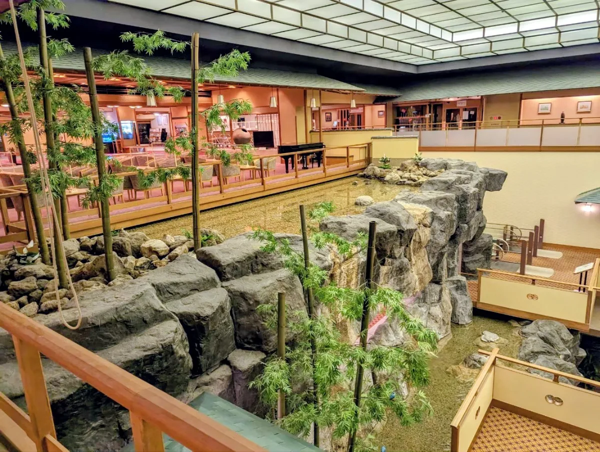 中庭步道與植栽下方的岩石造景,水流沿著岩石形成室內瀑布