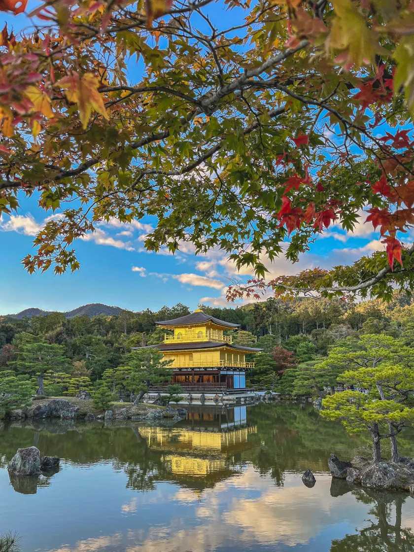 The Golden Pavilion and its reflection in the pond, framed by autumn foliage at Kinkaku-ji.
