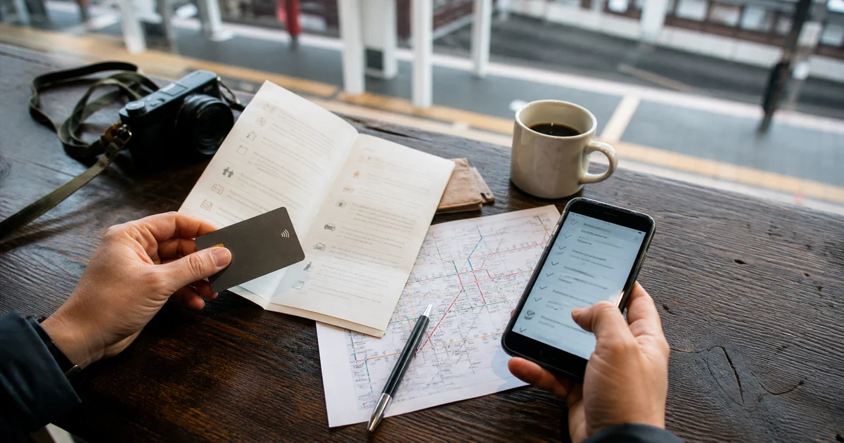 Illustrative travel preparation scene with a phone, payment card and checklist