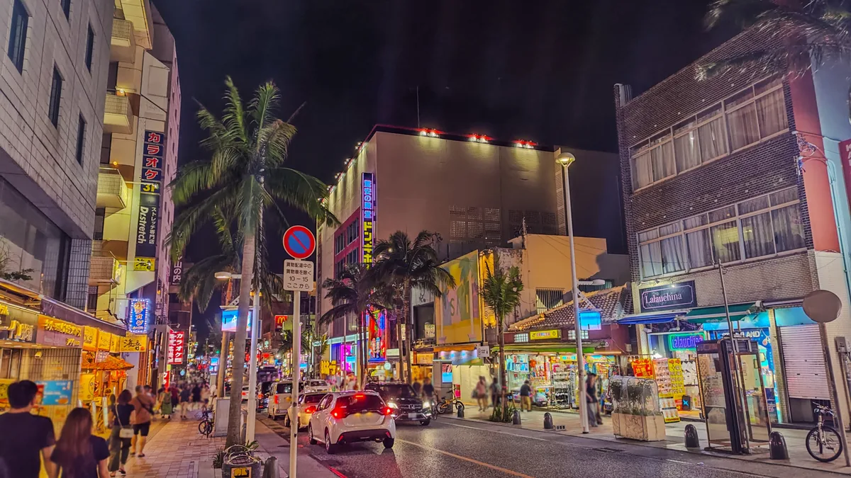 Kokusai Street at night with bright signs and palm trees