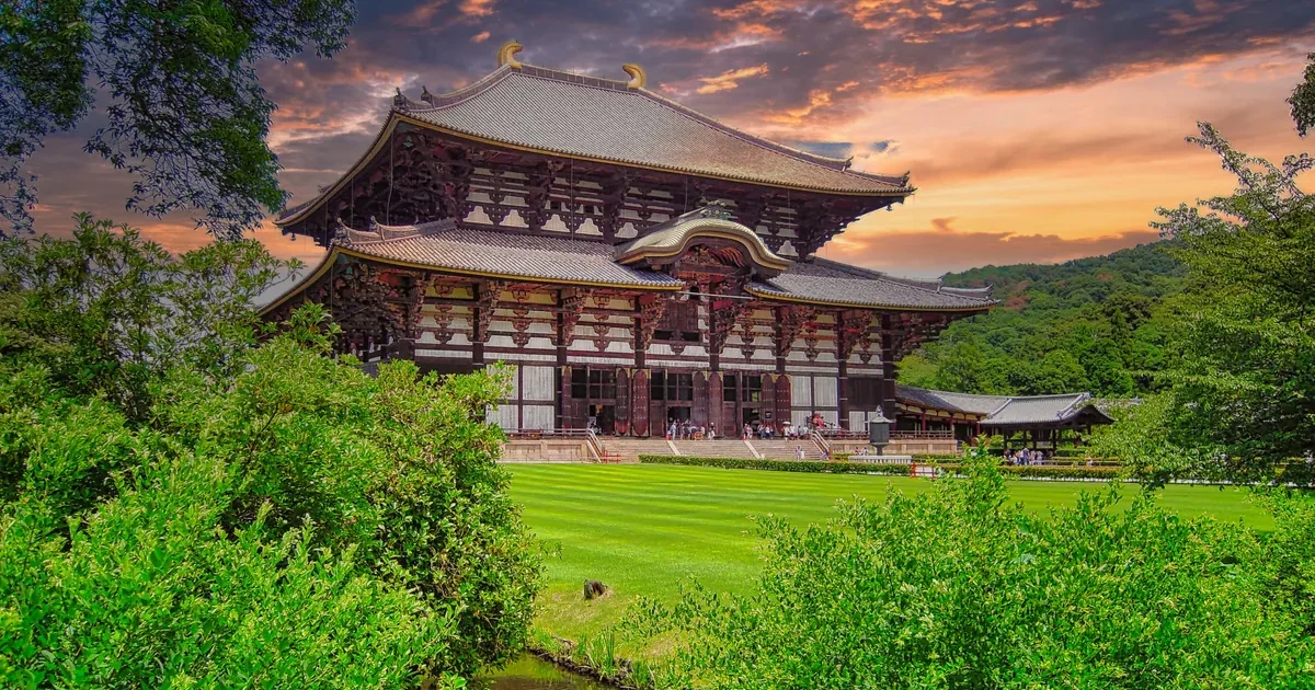 Todai-ji Great Buddha Hall framed by trees beneath a dramatic evening sky