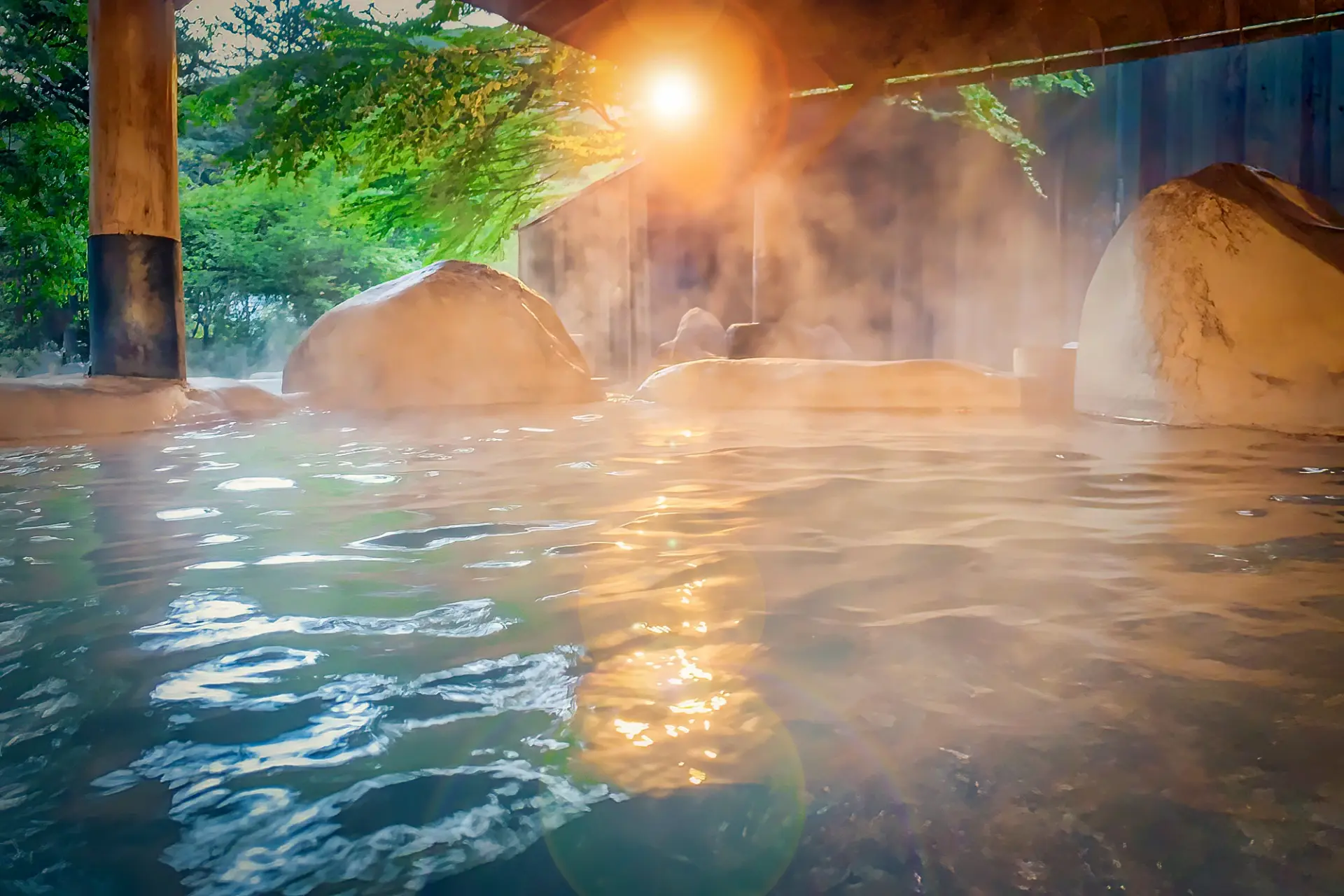 Steam rising from a traditional Japanese rotenburo onsen at sunset