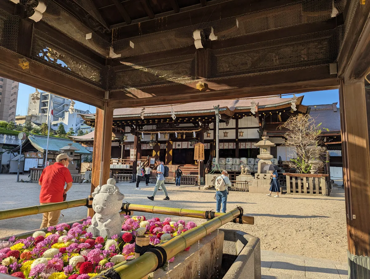 Pink, purple and yellow flowers filling a stone purification basin at Osaka Tenmangu