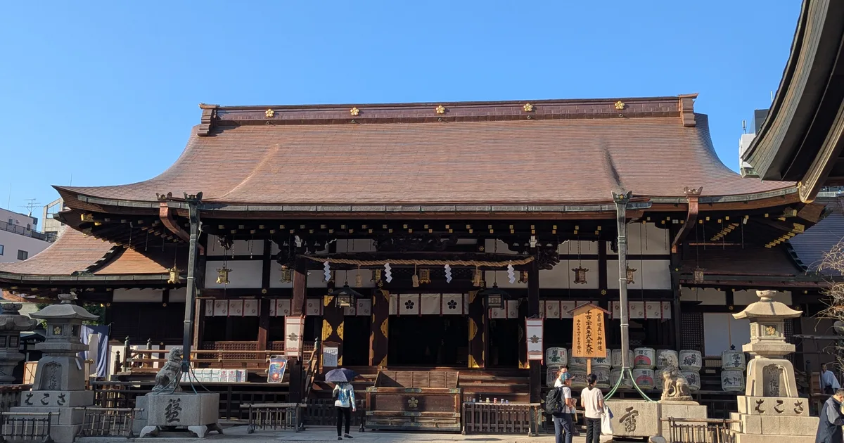 Osaka Tenmangu's wooden worship hall and stone lanterns beneath a clear blue sky