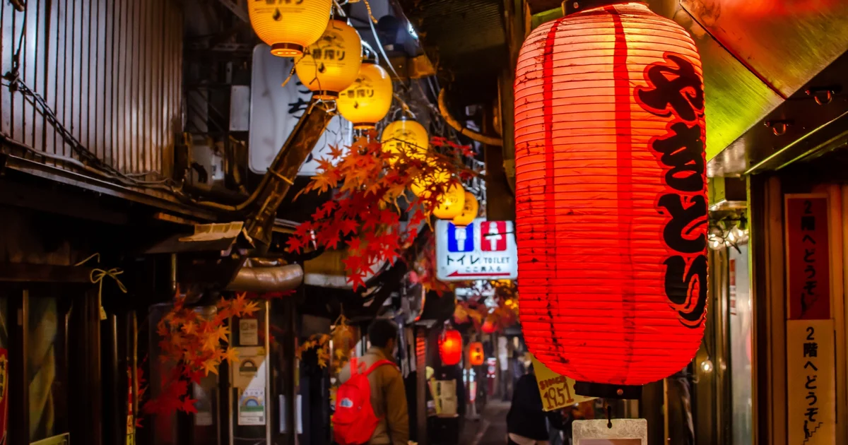 Red and yellow lanterns above a narrow restaurant alley in Japan