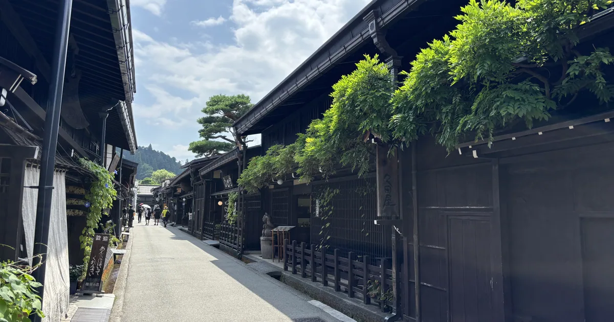A quiet Takayama street lined with dark wooden buildings beneath a blue sky