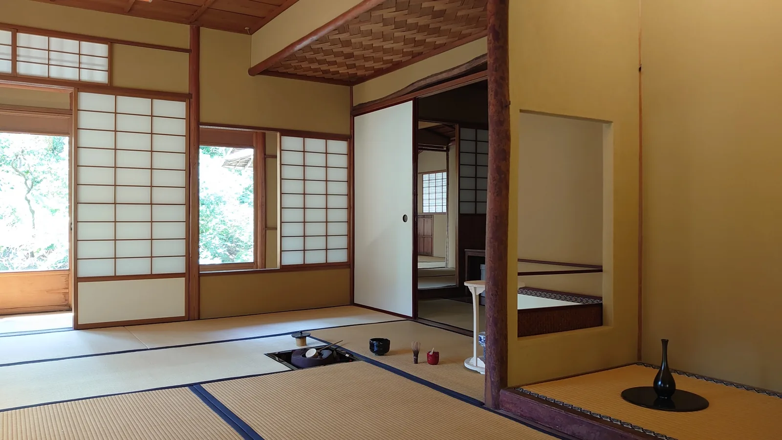 Daylight entering a traditional tatami tea room, with tea utensils beside a sunken hearth