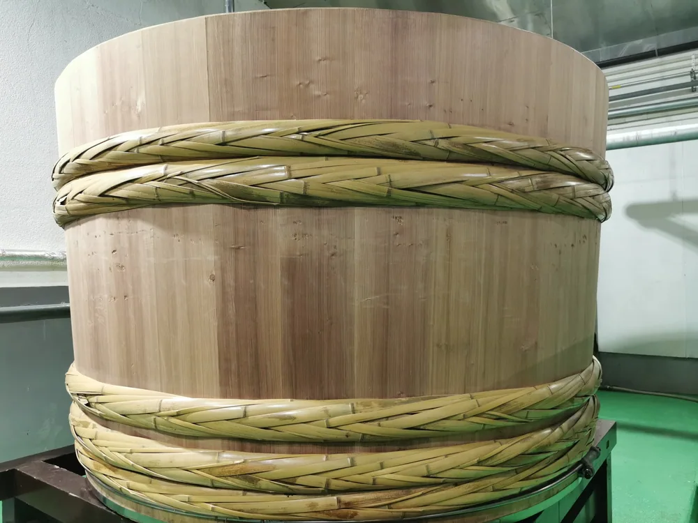 A large pale wooden vessel bound with thick rope, photographed indoors