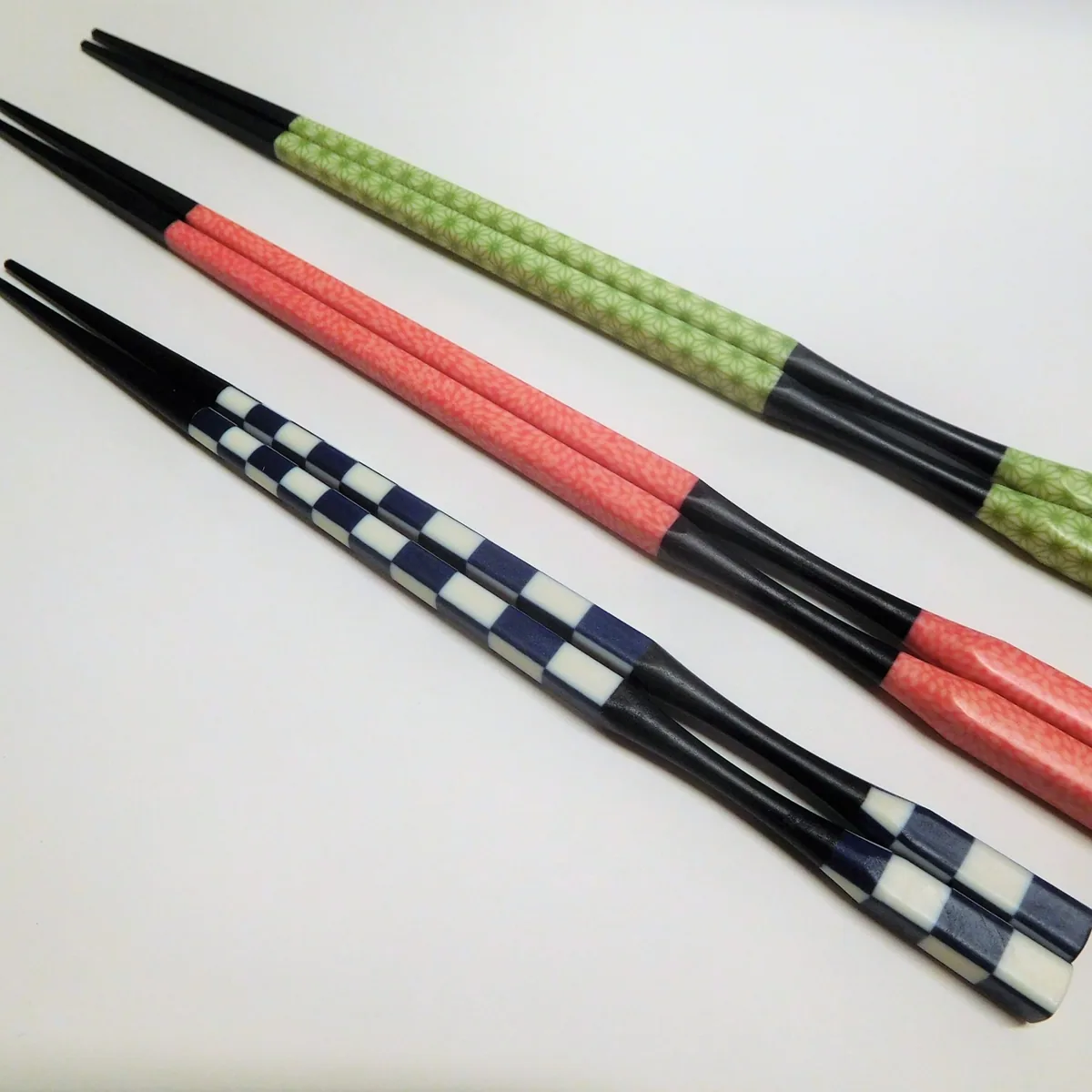 Three pairs of patterned Japanese chopsticks arranged on a light surface