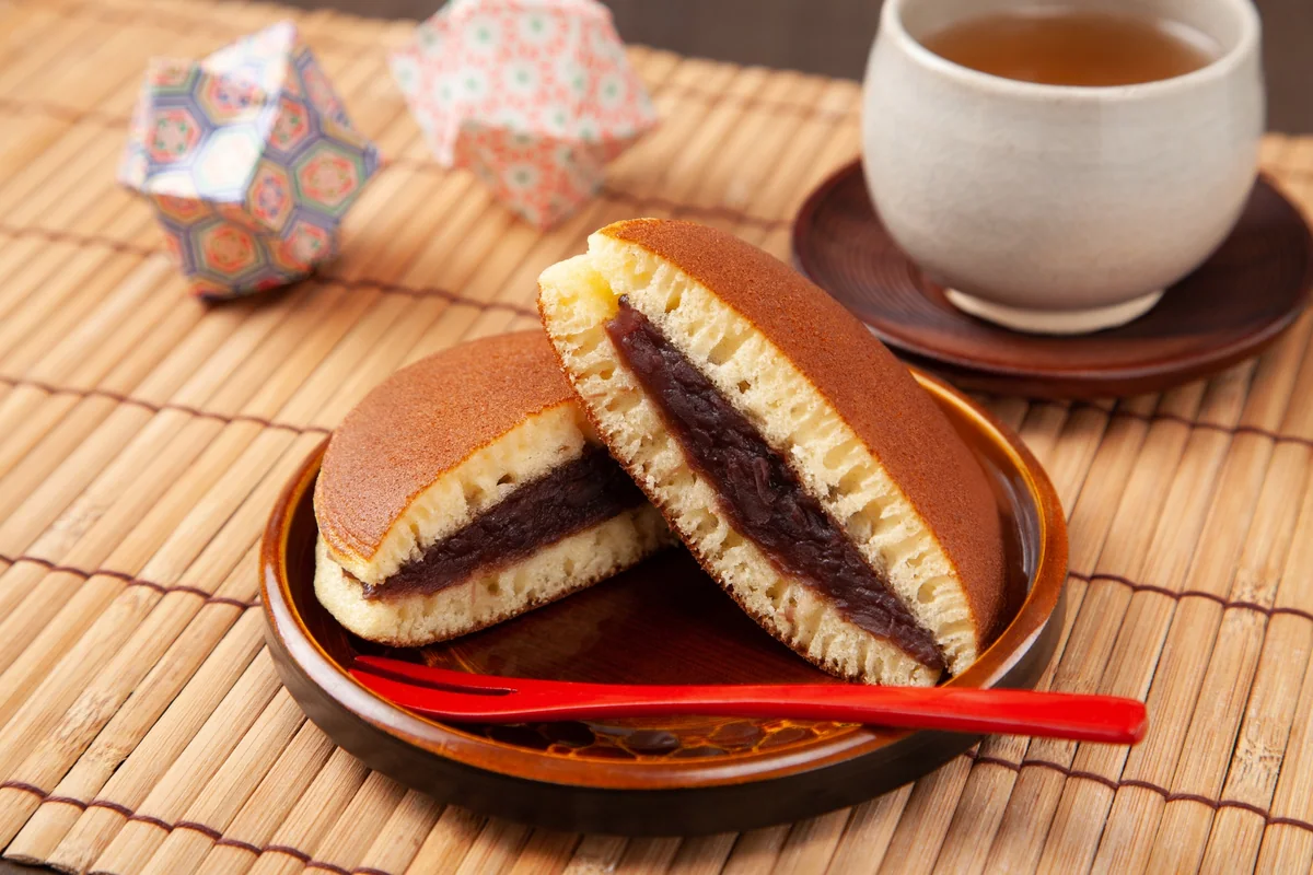 Dorayaki cut in half to show its sweet bean filling, served beside a cup of tea