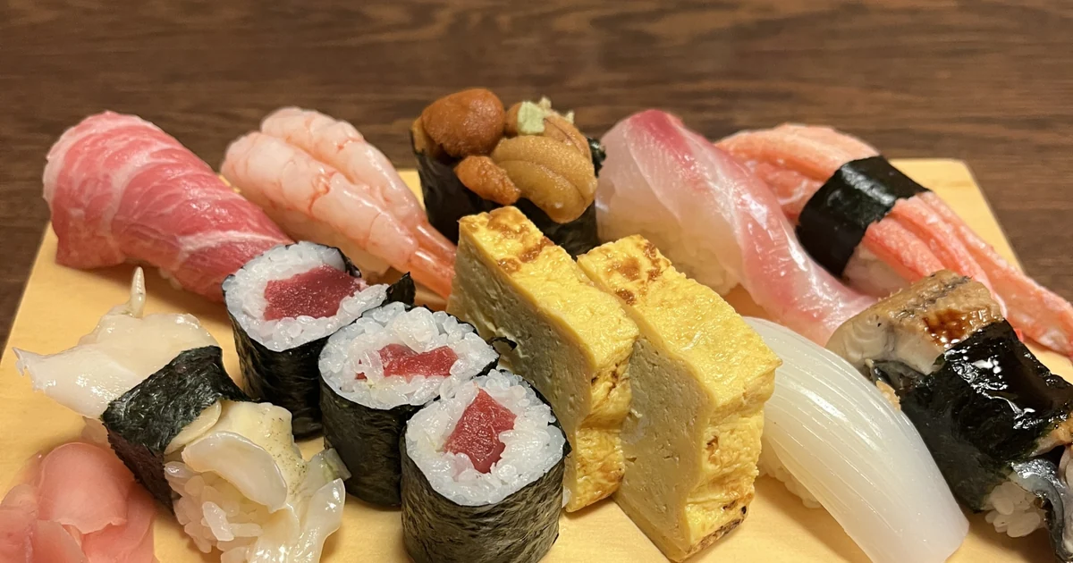 An assortment of nigiri sushi, rolled sushi and tamagoyaki on a wooden serving board