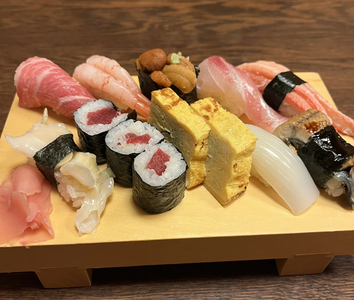 Nigiri sushi, rolled sushi and tamagoyaki arranged together on a wooden board