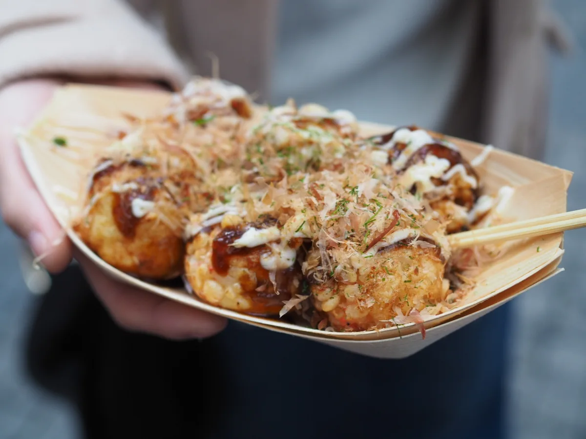 A tray of takoyaki topped with sauce, mayonnaise and bonito flakes