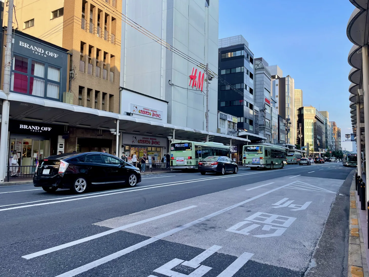 Shijo street in central Kyoto with covered shopping sidewalks, city buses and taxis