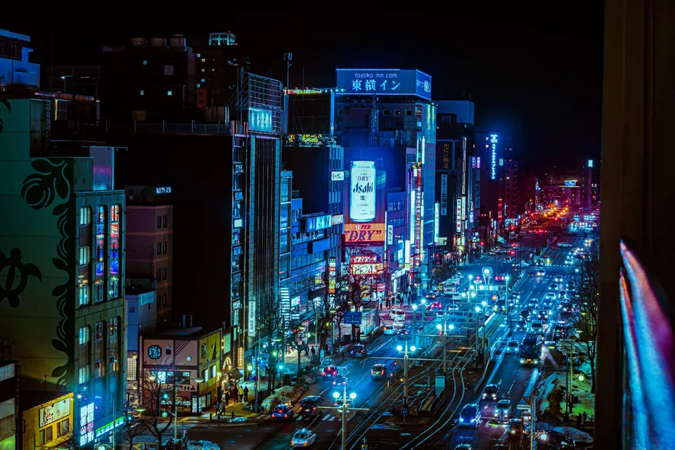 Trams and traffic on a brightly lit street in Susukino at night