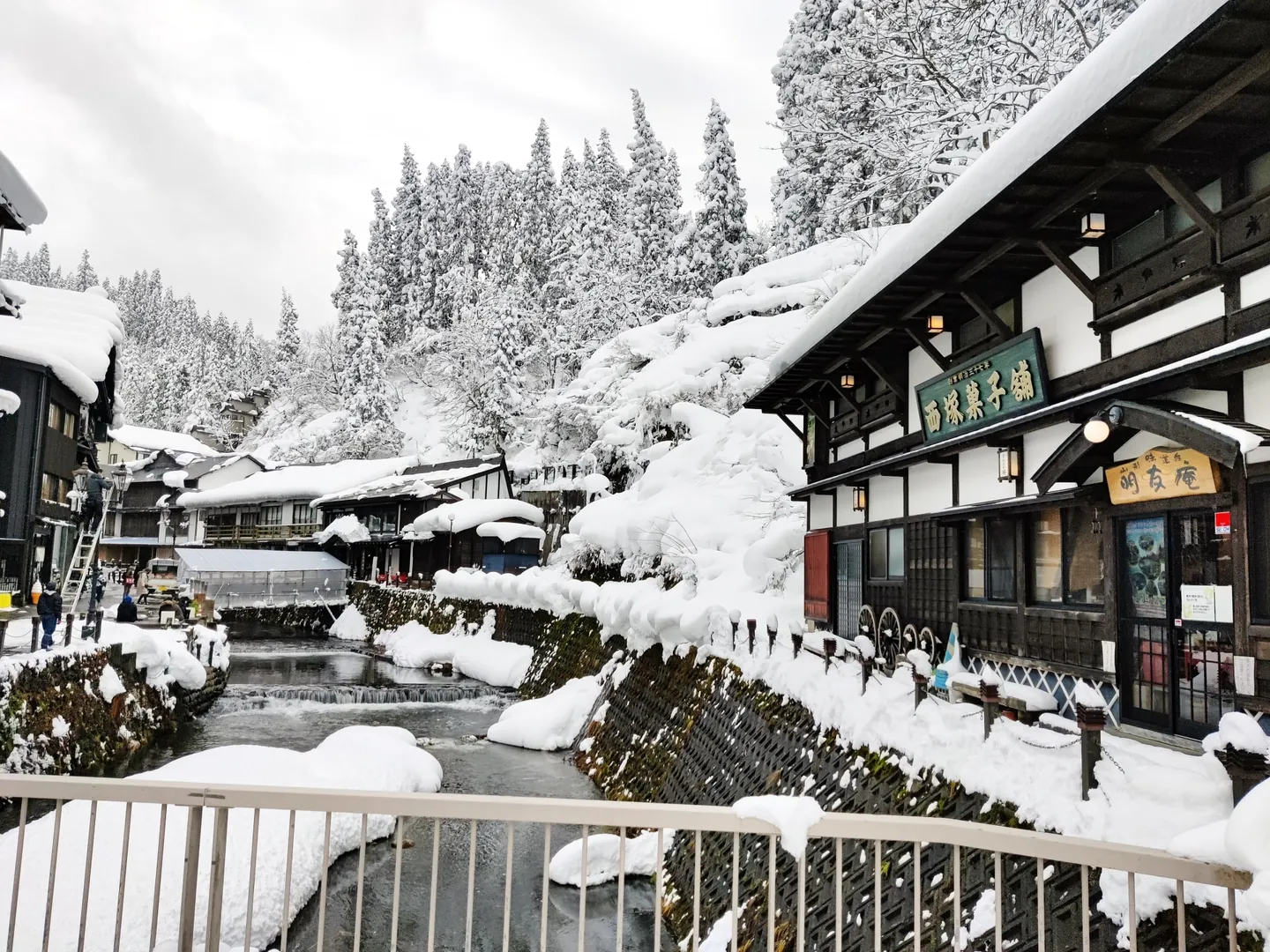 Snow-covered roofs and bridges along the river between Ginzan Onsen's wooden inns